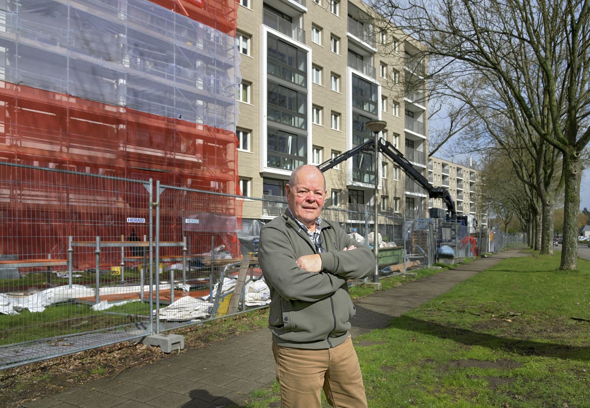 Theo met z'n armen over elkaar voor de flat aan de mendelssohnstraat in de steigers